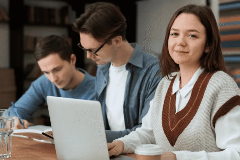 A group of people sitting at a table and working on laptops.