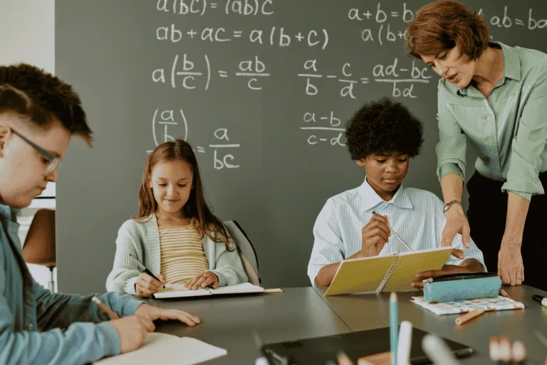 A teacher helping students with their homework in a classroom.